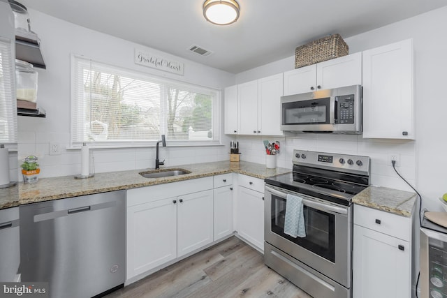 kitchen featuring a sink, stainless steel appliances, visible vents, and white cabinets