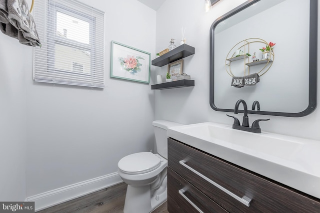 bathroom with toilet, vanity, baseboards, and wood finished floors