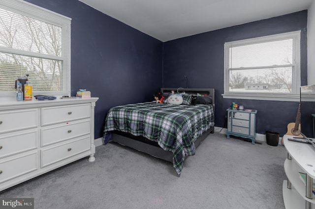 bedroom with multiple windows, baseboards, and light carpet