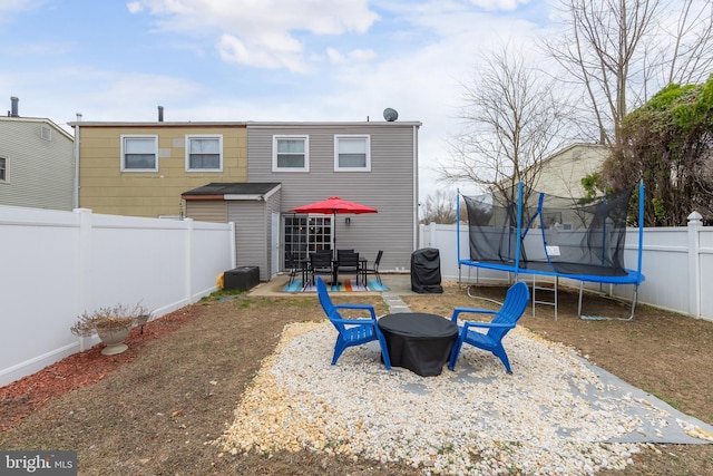 rear view of house with a patio area, a fenced backyard, an outdoor fire pit, and a trampoline