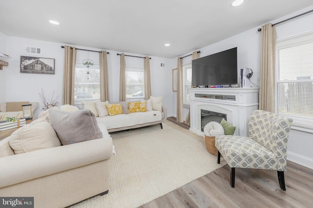 living room featuring recessed lighting, wood finished floors, visible vents, and a healthy amount of sunlight