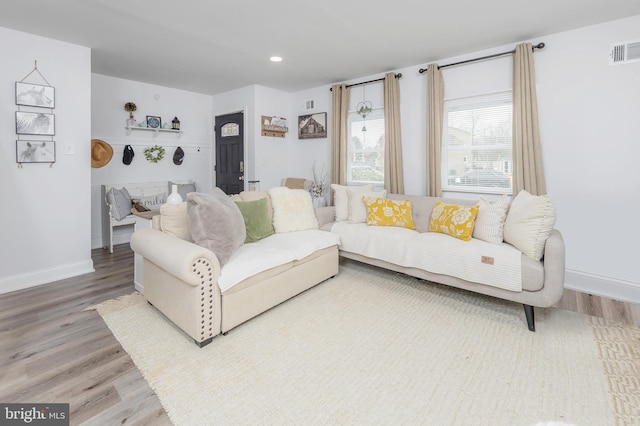 living area featuring visible vents, baseboards, and wood finished floors