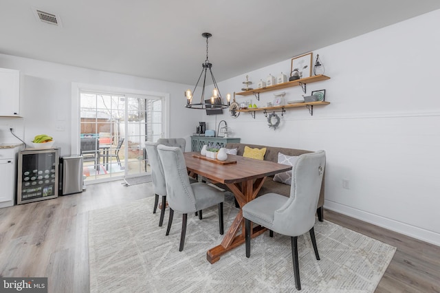 dining room with wine cooler, a notable chandelier, visible vents, and light wood-type flooring