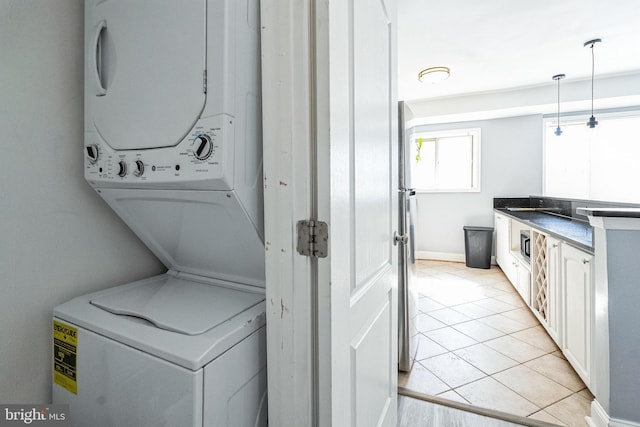 laundry room featuring light tile patterned floors, laundry area, and stacked washer / drying machine