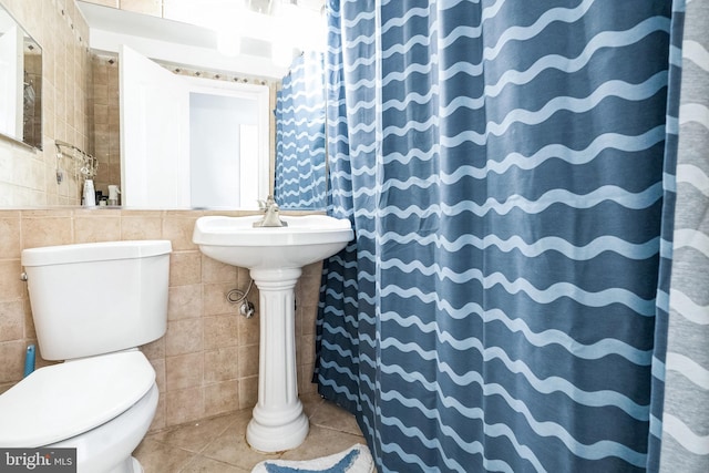 full bathroom with tile patterned flooring, tile walls, curtained shower, and toilet