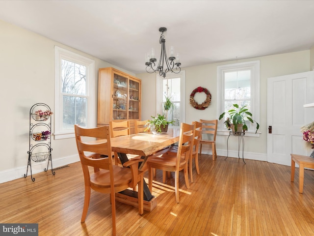 dining area with light wood-style flooring, plenty of natural light, baseboards, and a chandelier