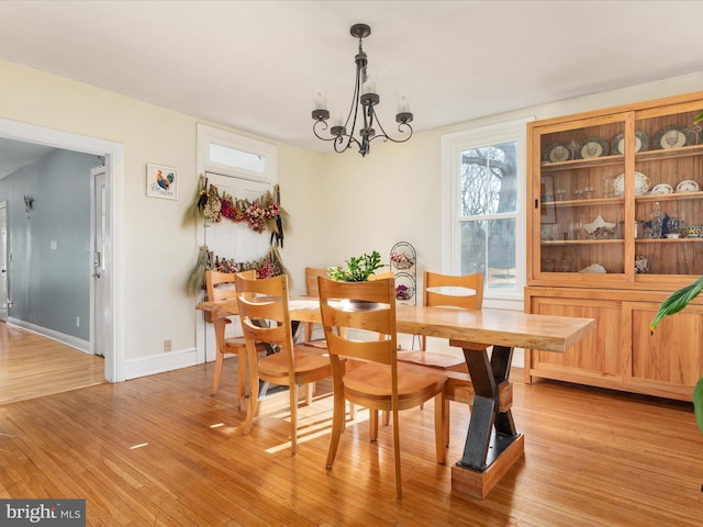 dining room with an inviting chandelier, light wood-style flooring, and baseboards