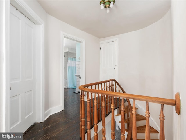 corridor with baseboards, an upstairs landing, and dark wood finished floors