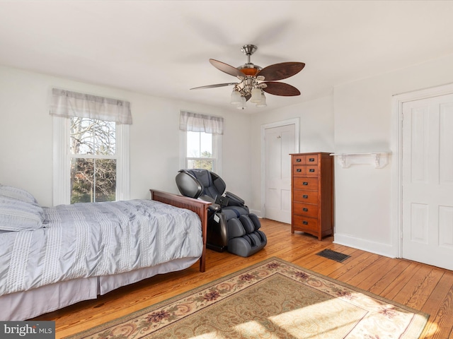 bedroom featuring visible vents, a ceiling fan, baseboards, and hardwood / wood-style floors