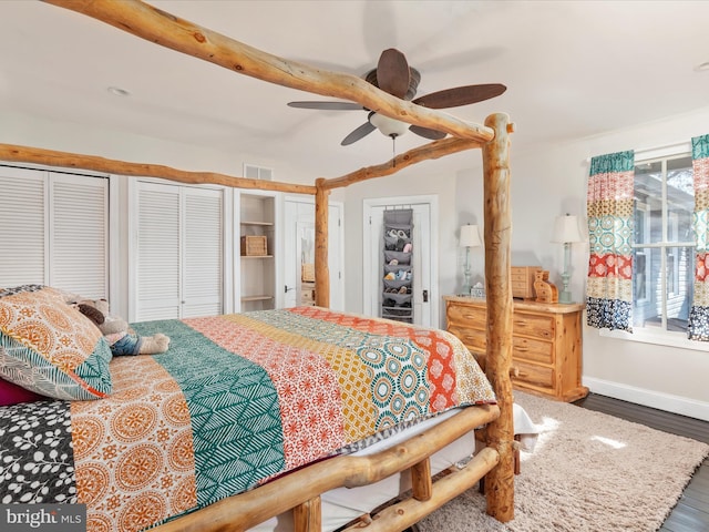 bedroom with visible vents, multiple closets, baseboards, wood finished floors, and a ceiling fan