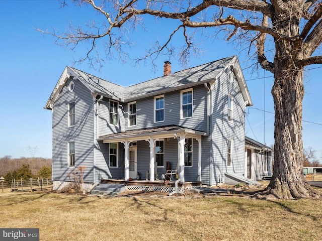 view of front of home featuring a front lawn, a porch, a chimney, and fence