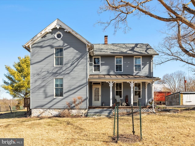 view of front of property with a front lawn, covered porch, and a chimney