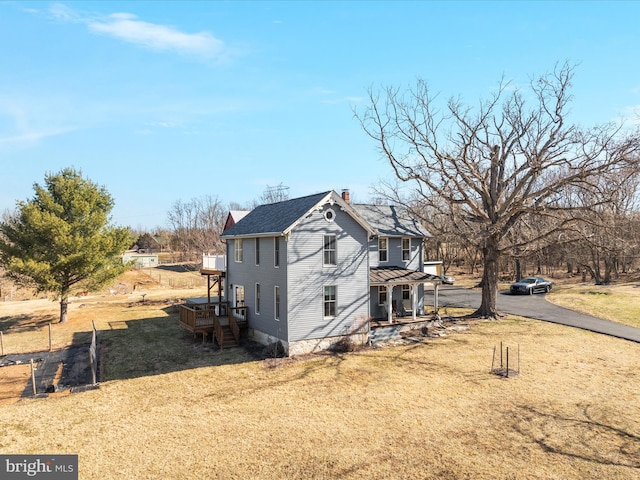 view of side of home featuring a lawn, roof with shingles, and a chimney