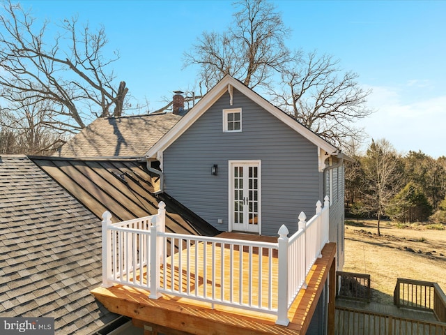 exterior space featuring french doors, a chimney, roof with shingles, and a wooden deck