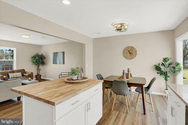 kitchen with white cabinetry, light wood-type flooring, and baseboards