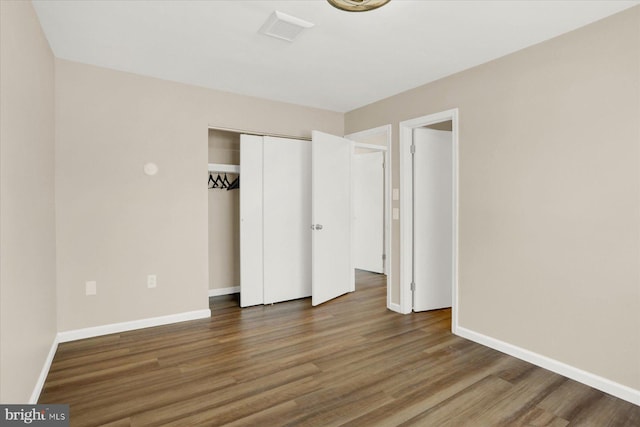 unfurnished bedroom featuring visible vents, baseboards, a closet, and wood finished floors