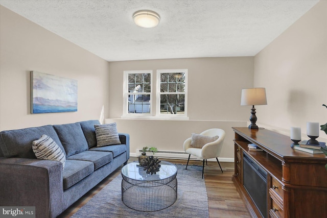 living area featuring a baseboard radiator, baseboards, a textured ceiling, and wood finished floors