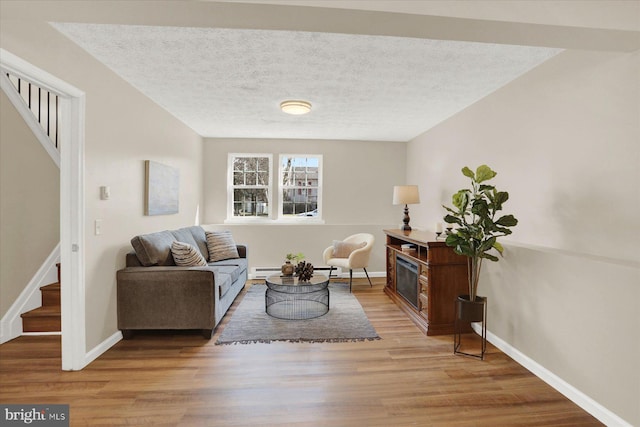 living room with a textured ceiling, stairs, and wood finished floors