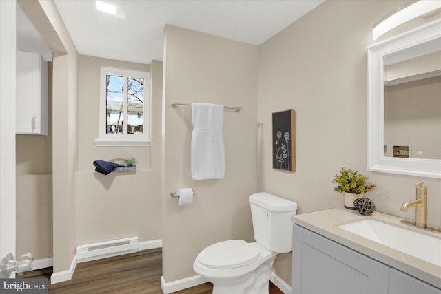 bathroom featuring baseboards, toilet, wood finished floors, vanity, and a baseboard radiator