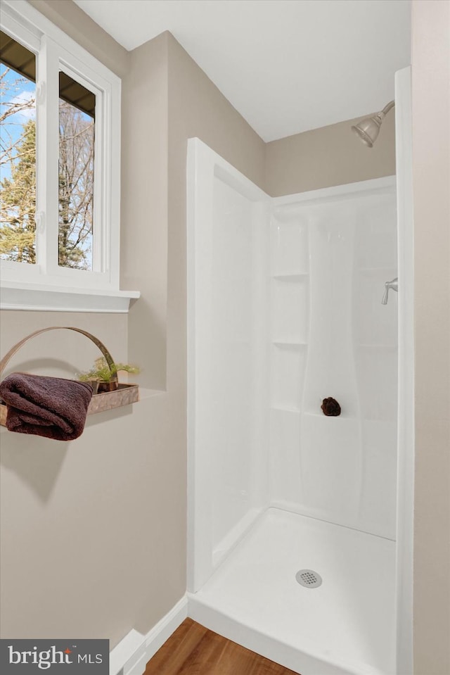 full bathroom featuring wood finished floors, a shower, and baseboards