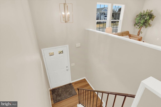 entrance foyer with a chandelier, baseboards, and wood finished floors