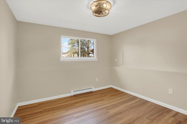 spare room featuring baseboard heating, baseboards, and wood finished floors