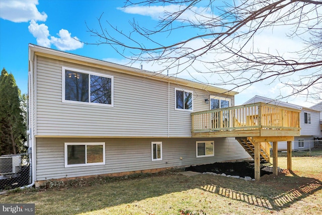 back of house featuring a wooden deck, a lawn, stairs, and fence