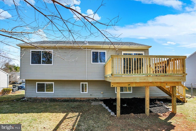 back of property with a deck, a yard, and fence