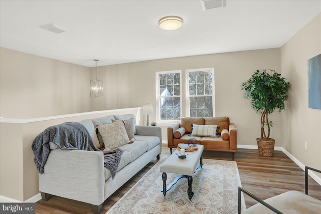 living area with an inviting chandelier, baseboards, visible vents, and dark wood-style flooring