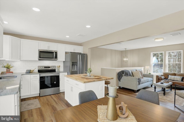 kitchen with visible vents, backsplash, wooden counters, stainless steel appliances, and a sink