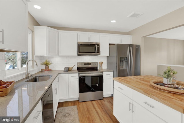 kitchen featuring visible vents, a sink, appliances with stainless steel finishes, white cabinetry, and tasteful backsplash