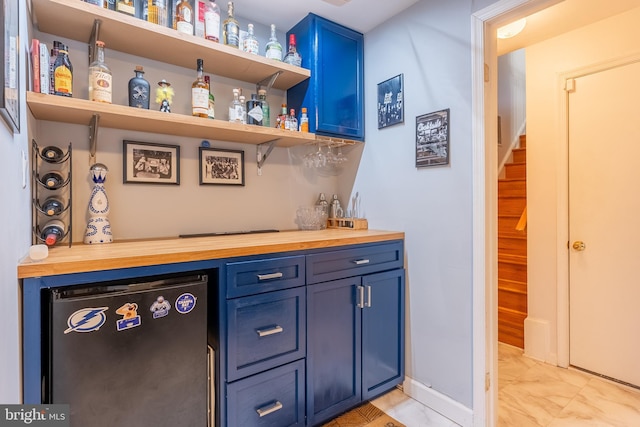 bar with fridge, a dry bar, baseboards, and marble finish floor