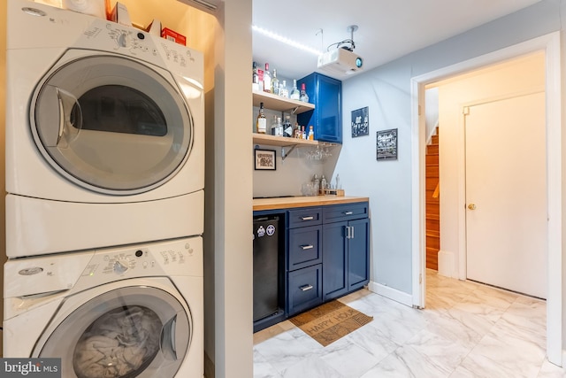 laundry room featuring wet bar, laundry area, marble finish floor, and stacked washing maching and dryer