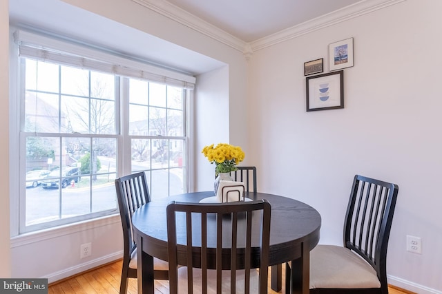 dining room with light wood-type flooring, baseboards, and ornamental molding