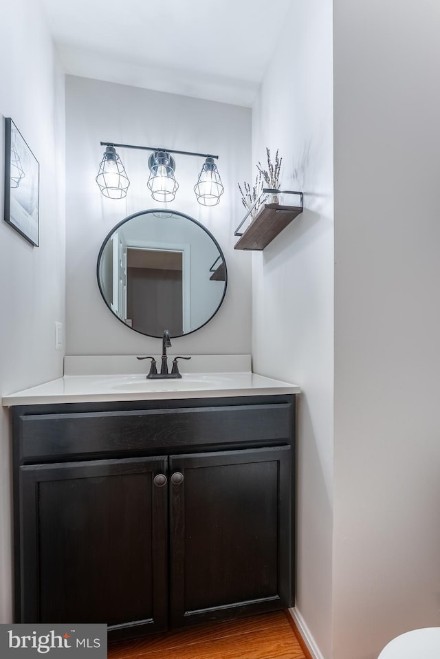 bathroom with baseboards, wood finished floors, and vanity