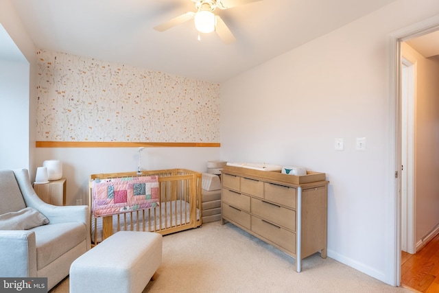 bedroom featuring light carpet, wallpapered walls, baseboards, and a ceiling fan