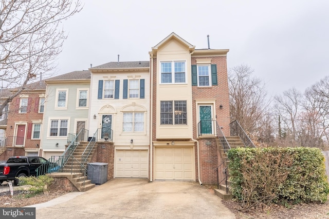 multi unit property featuring brick siding, stairway, concrete driveway, and a garage