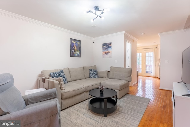 living area with a notable chandelier, light wood-style floors, and crown molding