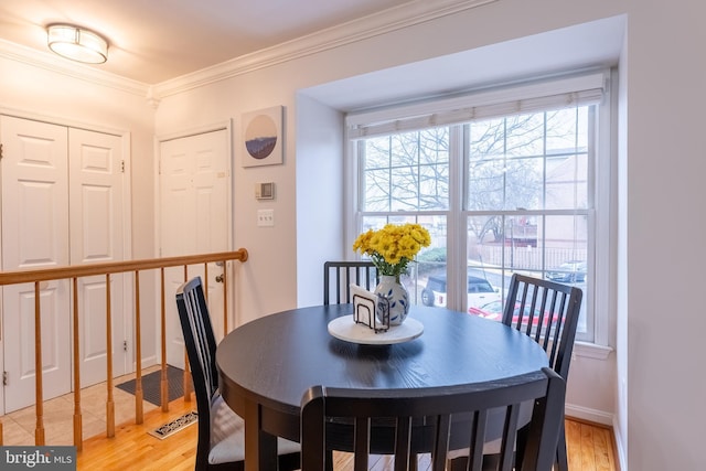 dining room with light wood-style flooring, baseboards, and ornamental molding