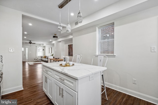 kitchen featuring visible vents, a kitchen island, ceiling fan, dark wood finished floors, and white cabinets