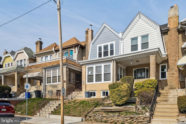 multi unit property featuring stairs, brick siding, and a gambrel roof