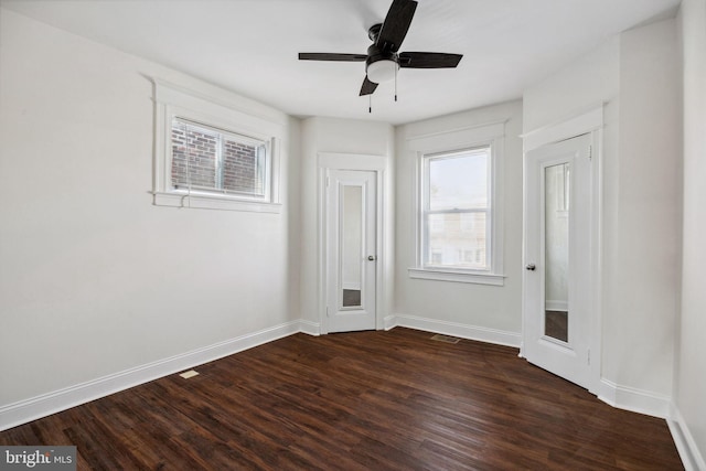 spare room featuring dark wood-style floors, ceiling fan, and baseboards