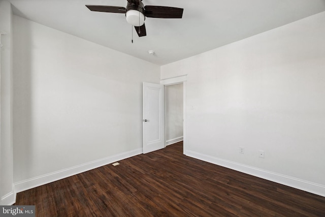 spare room featuring baseboards, ceiling fan, and dark wood-style flooring