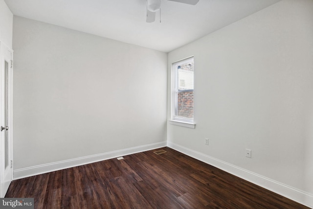 spare room featuring a ceiling fan, visible vents, dark wood-style flooring, and baseboards