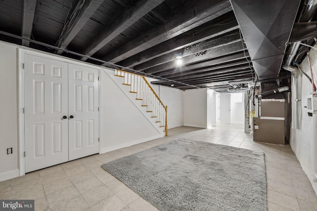 finished basement with tile patterned floors, baseboards, and stairs