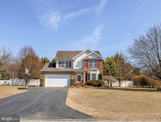 traditional-style home featuring a front lawn, driveway, fence, an attached garage, and brick siding