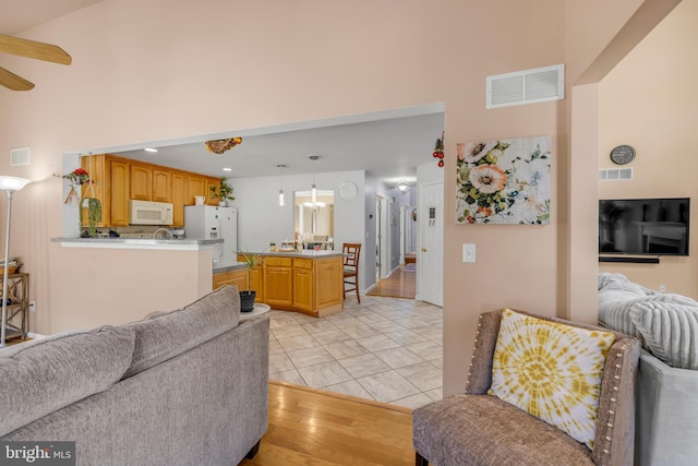 living room featuring a high ceiling, visible vents, and ceiling fan