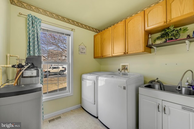 clothes washing area with visible vents, a sink, washing machine and dryer, cabinet space, and baseboards