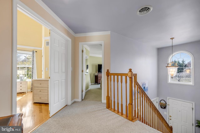 corridor with visible vents, light wood finished floors, baseboards, an inviting chandelier, and an upstairs landing