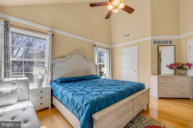 bedroom featuring visible vents, light wood finished floors, and high vaulted ceiling